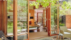 A traditional Japanese-style room with sliding doors, a bed, a sofa, and a small table with a teapot. - Sticky Rice Villas (Stirling)