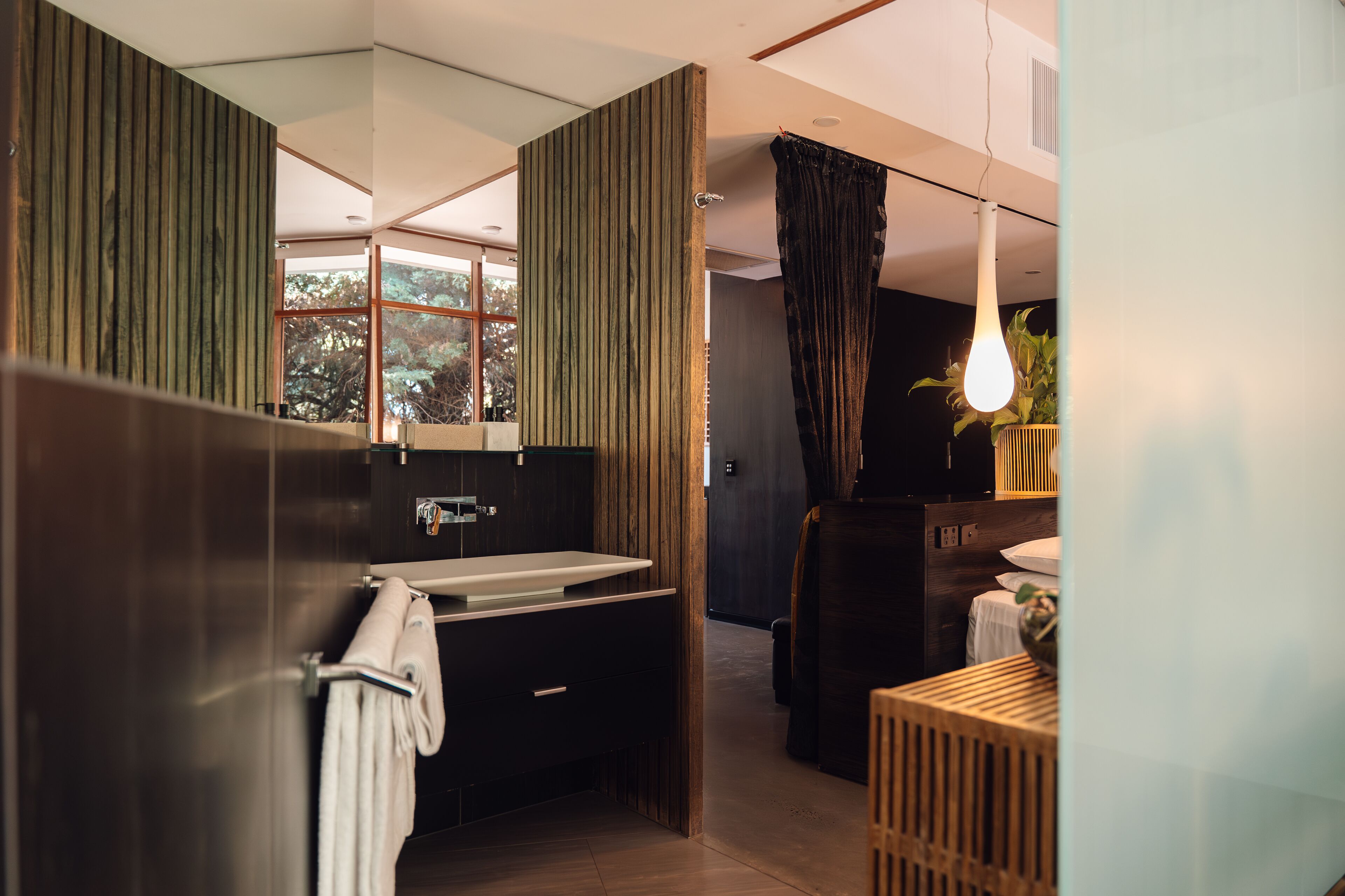 A modern bathroom with a large mirror, a sink, and a shower area.