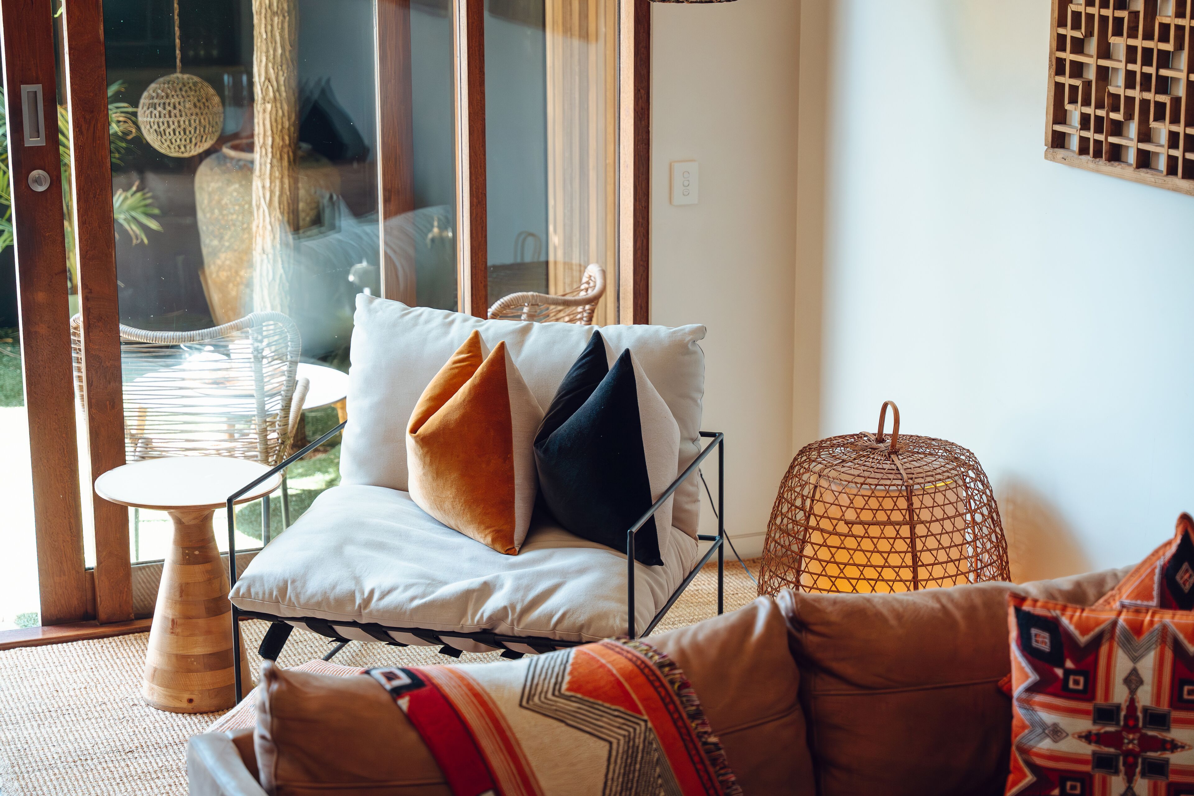 Un salon confortable avec un canapé, des coussins, une petite table ronde et un fauteuil en osier.