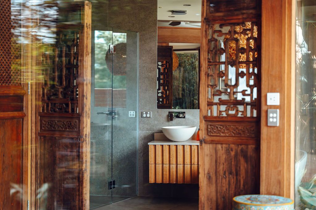 Un baño moderno con ducha de vidrio, tocador de madera y un espejo grande.