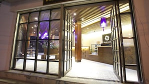A hotel entrance with large glass doors, a reception desk, and a sign above the door. - Nakorn de Sukhothai hip hotel (Sukhothai)