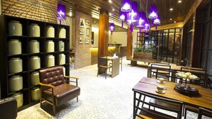 A cozy interior with a brick wall, a leather chair, and a dining area with a table set for tea. - Nakorn de Sukhothai hip hotel (Sukhothai)