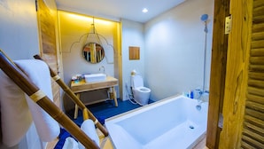 A bathroom with a bathtub, toilet, sink, and a wooden chair. - Nakorn de Sukhothai hip hotel (Sukhothai)