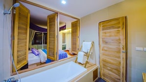 A bathroom with a large mirror, wooden doors, a bathtub, and a shower. - Nakorn de Sukhothai hip hotel (Sukhothai)