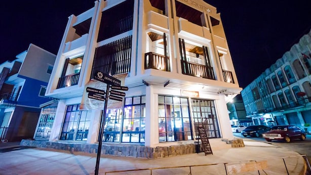 A multi-story building with a sign for 'Hong Rama' and directional signs for nearby locations. - Nakorn de Sukhothai hip hotel (Sukhothai)
