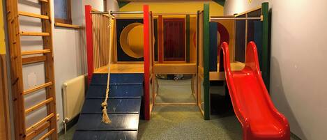 A children's play area with a slide, climbing structure, and a rope ladder.