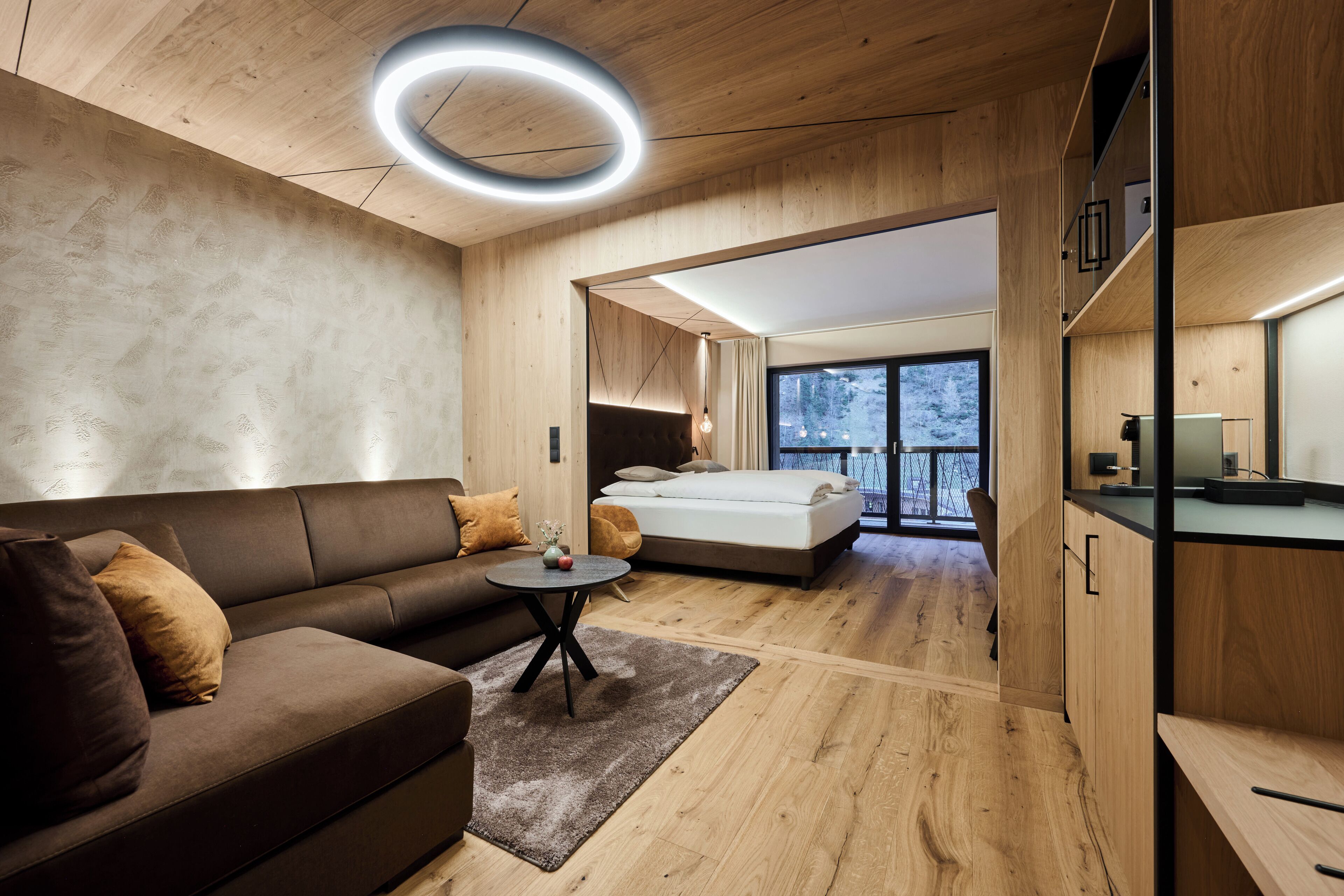A modern, well-lit room with a sofa, a small round table, and a bed.