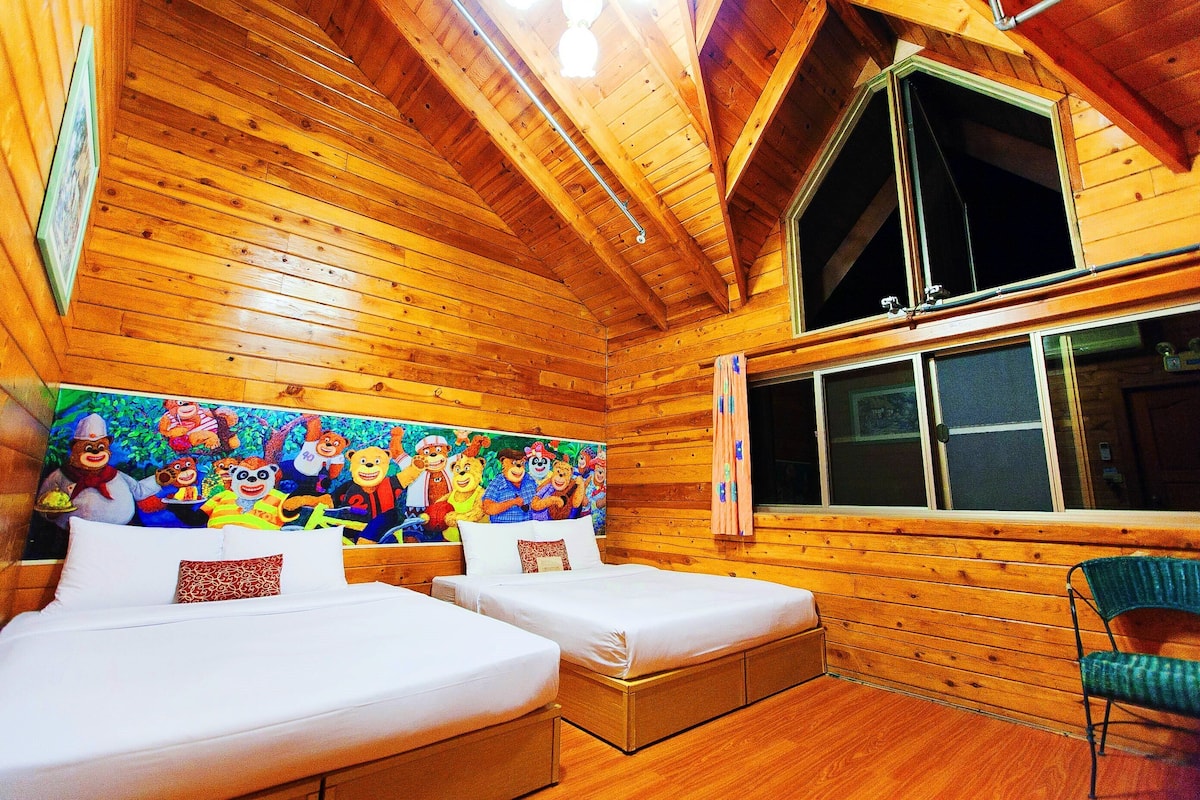 A wooden cabin room with two beds, a large mural, and a window.