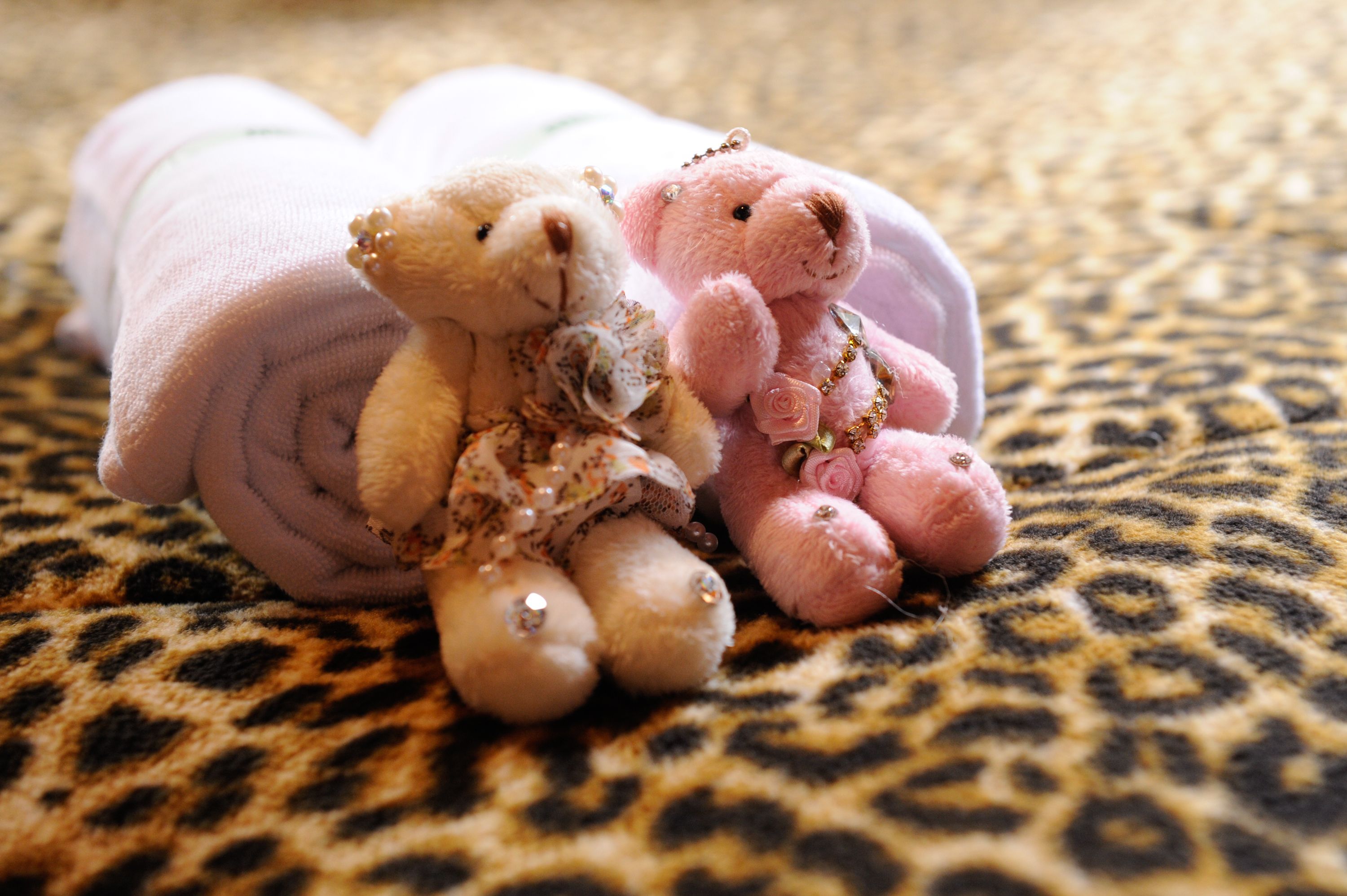 Two teddy bears on a leopard print fabric.