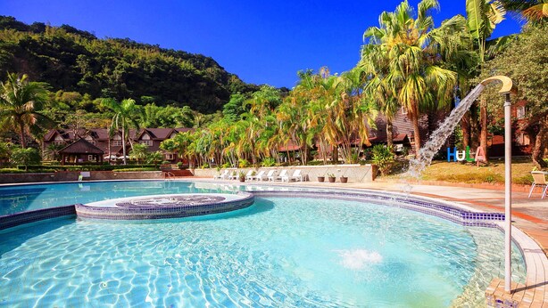 A swimming pool with a circular hot tub, surrounded by palm trees and a mountainous backdrop. - Master Bear Resort (Beinan)