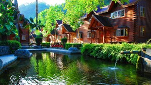 A wooden cabin-style hotel with a pond in the foreground. - Master Bear Resort (Beinan)