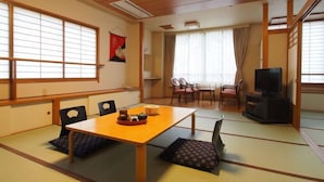 A traditional Japanese-style room with tatami flooring, a low table, and a television. - Tofuya Ryokan (Yonezawa)