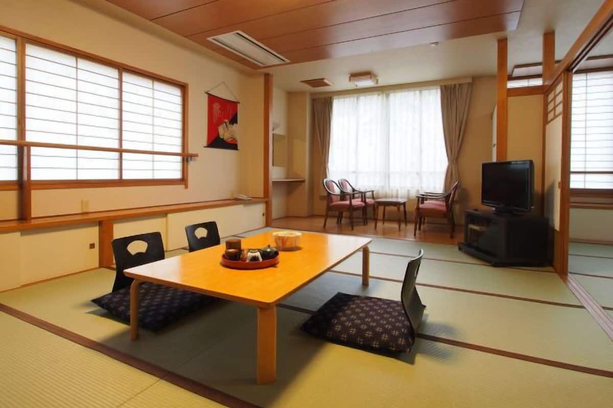 Una habitación tradicional japonesa con suelo de tatami, una mesa baja y un televisor.