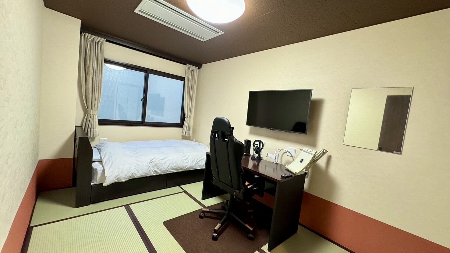 A hotel room with a bed, desk, chair, television, and a window.