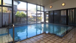 An indoor swimming pool with clear glass walls, a tiled floor, and a view of the outside. - Tofuya Ryokan (Yonezawa)