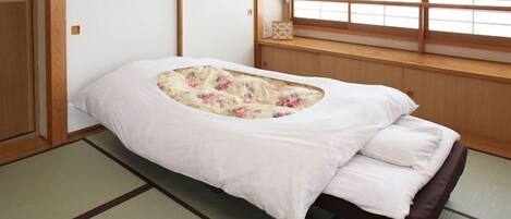 A traditional Japanese room with tatami flooring, a low bed with a floral-patterned mattress, and a window with wooden frames.