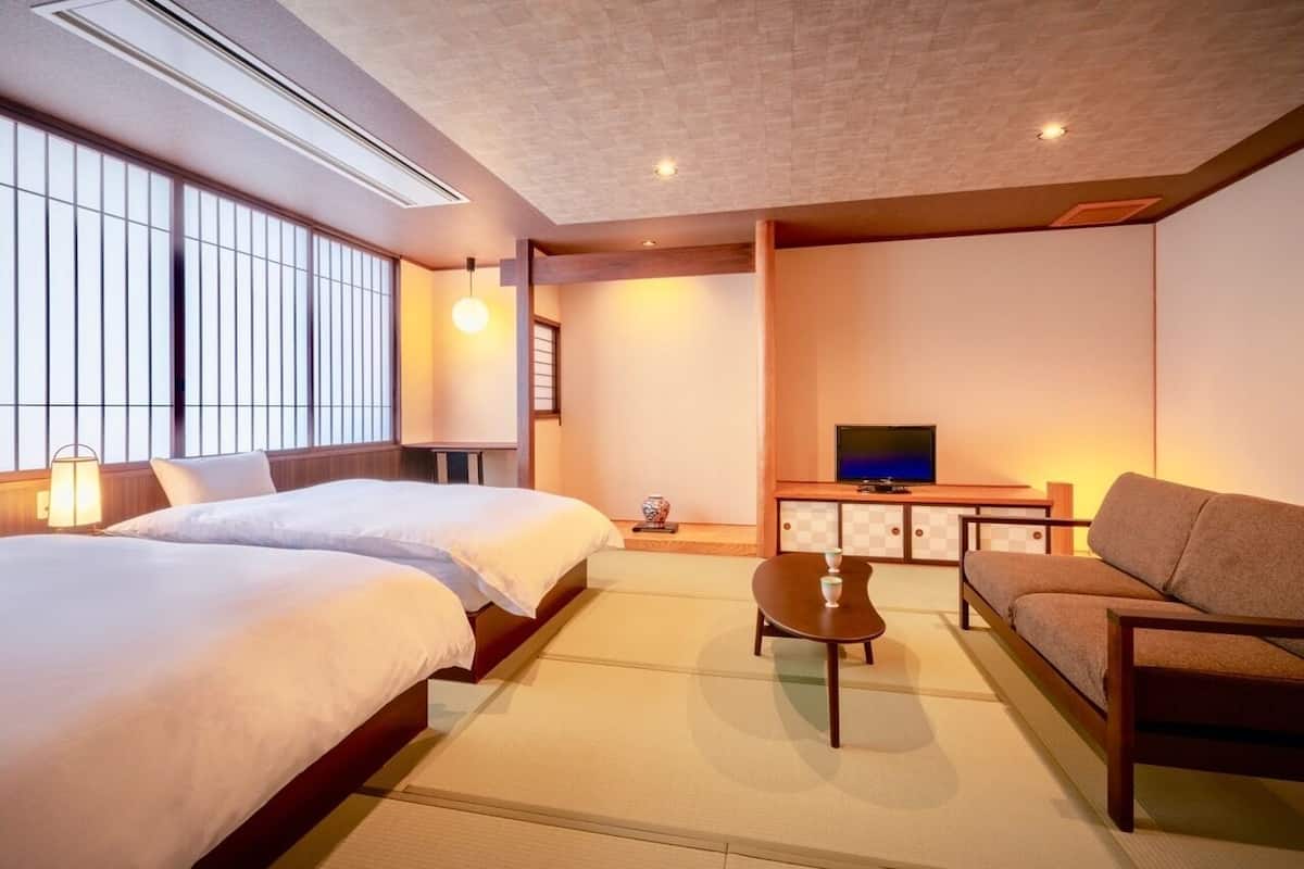 Habitación de hotel con cama, sofá, televisión y una mesita.