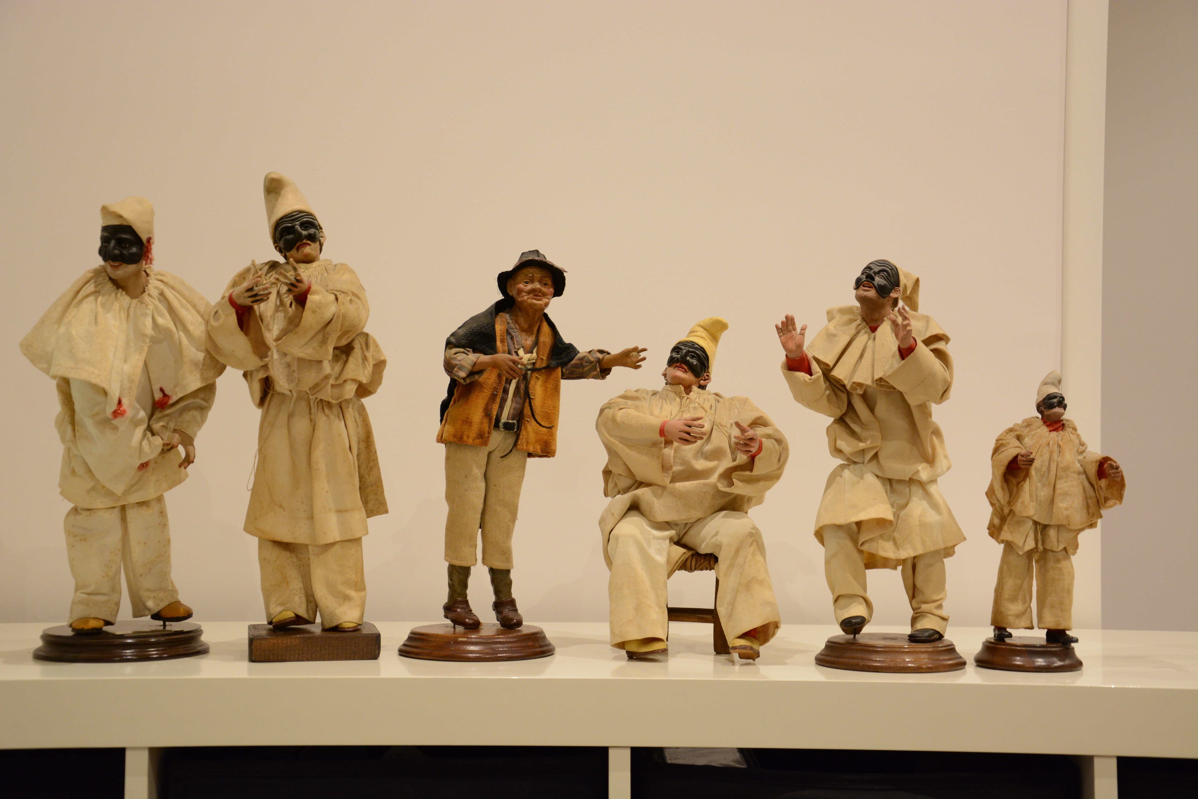A display of six figurines in traditional attire on a white surface.