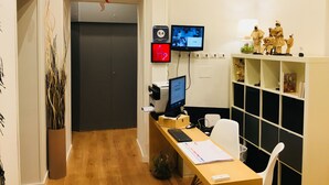 A reception area with a desk, computer monitors, a printer, and a shelf with figurines. - Grande Archivio Napoli 22 (Naples)