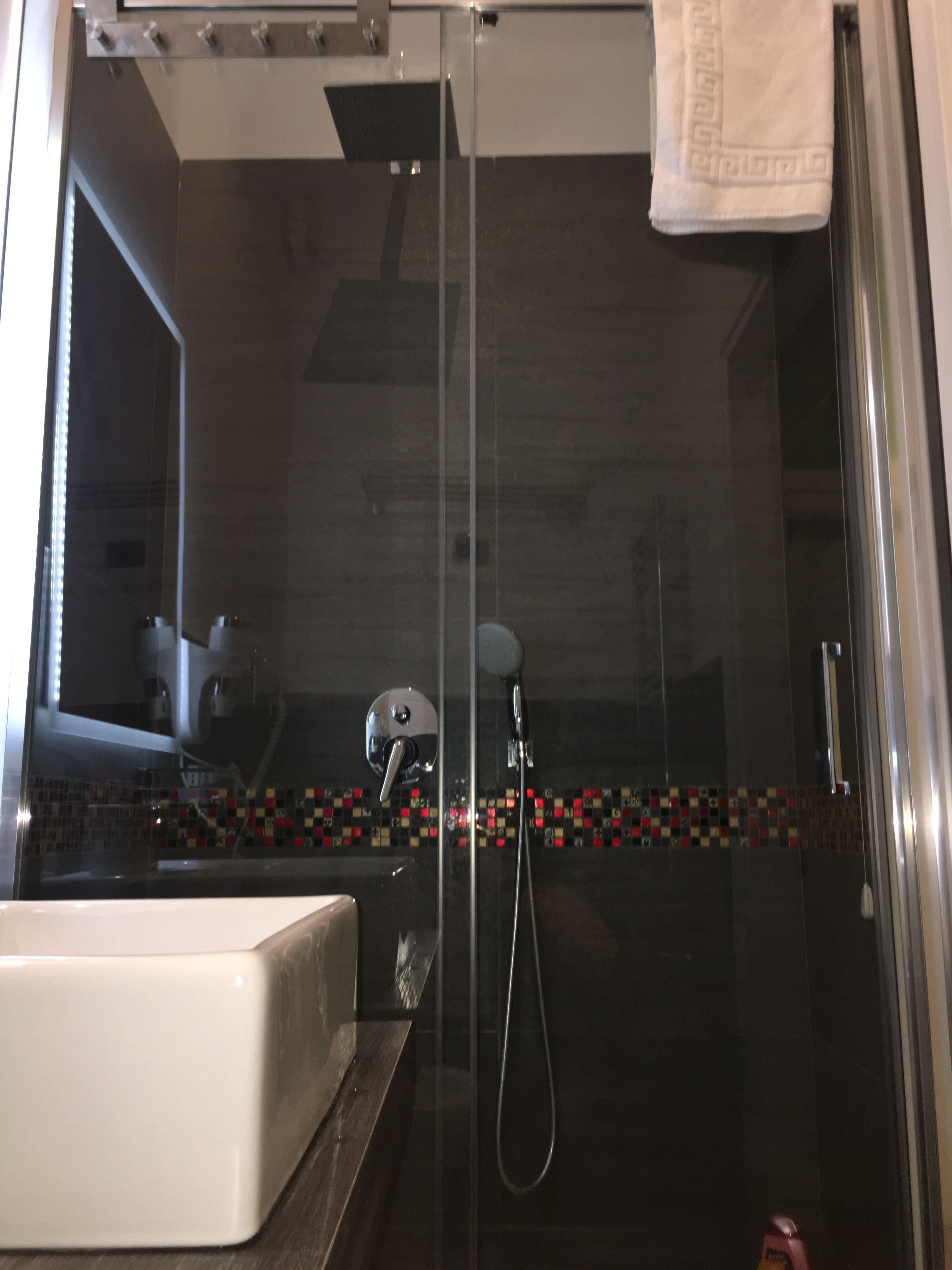 A modern bathroom with a glass shower enclosure, a white sink, and a tiled backsplash.