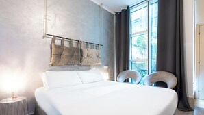 Un dormitorio moderno con una cama grande, una mesita de noche y una silla.