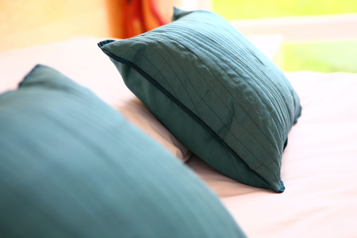 A close-up of two green pillows on a bed.