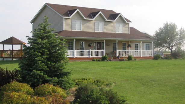 A two-story house with a front porch, a covered patio, and a well-maintained lawn.