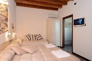 A bedroom with a bed, pillows, a wardrobe, an air conditioning unit, and a television on the wall. - CQ Rooms Verona (Verona)