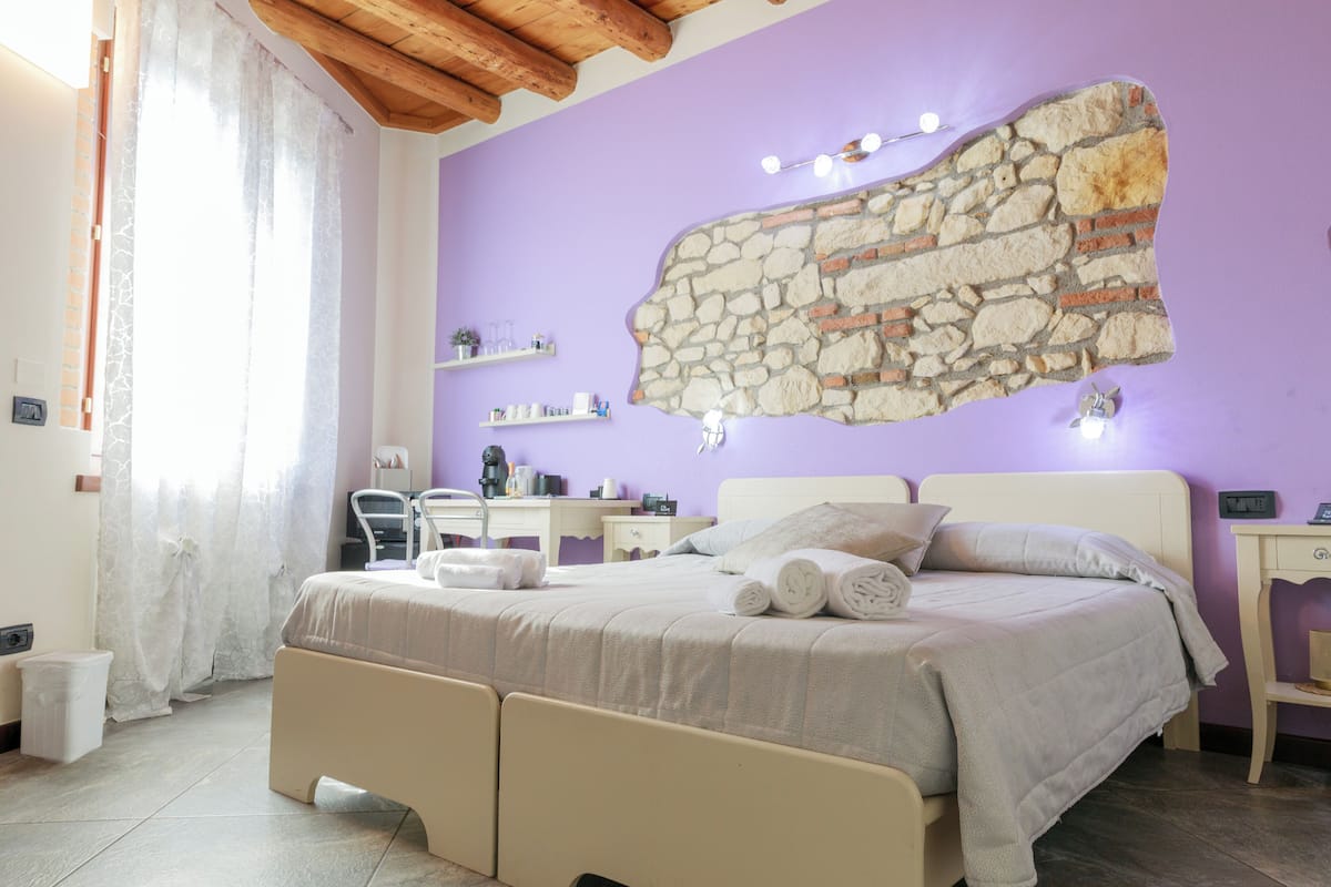 Ein Schlafzimmer mit Steinwand, einem Bett mit Kissen und Handtüchern, einem Schreibtisch und einem Stuhl.