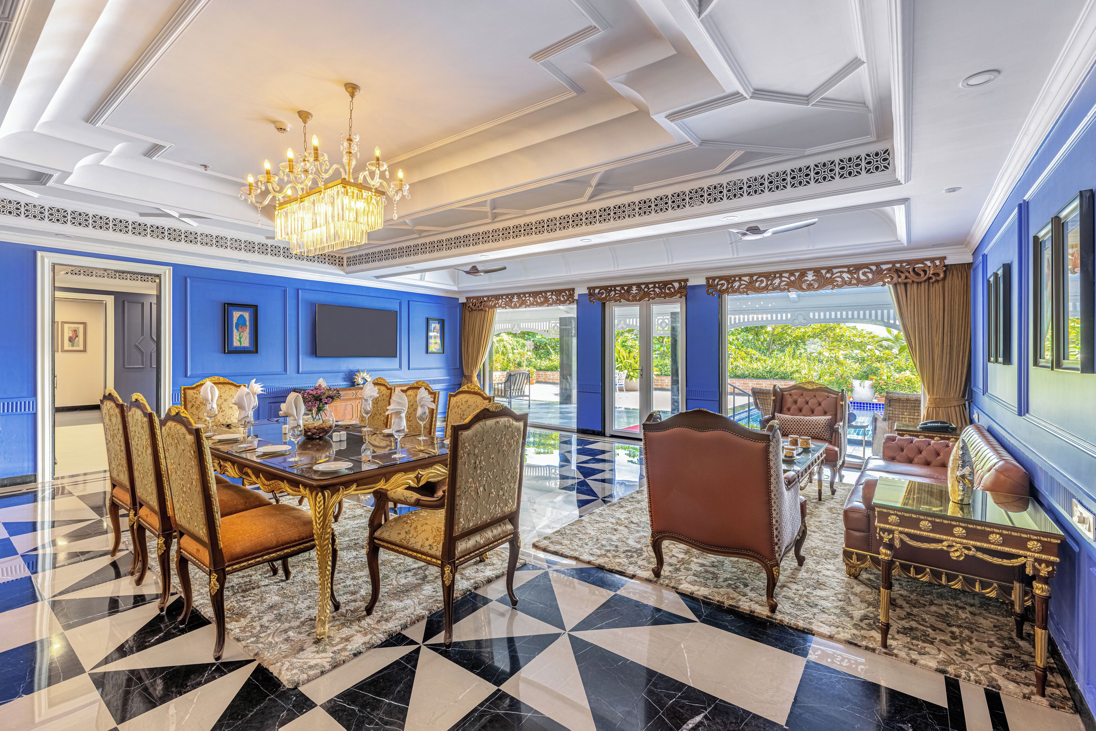 A luxurious dining room with a chandelier, a large table, and ornate chairs.