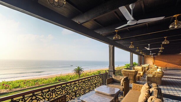 A balcony with wicker furniture, a view of the ocean, and a ceiling fan. - Mayfair Palm Beach Resort  (Brahmapur)