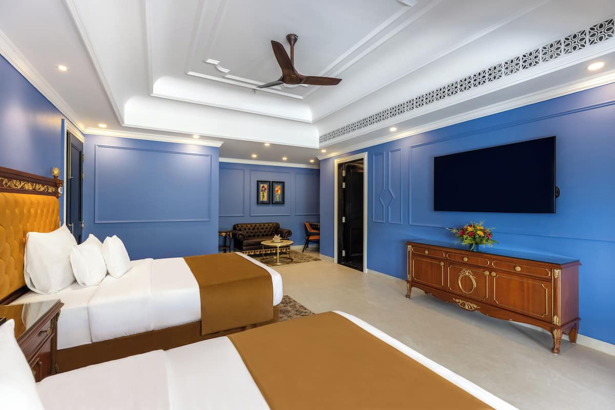A hotel room with a large bed, a TV mounted on the wall, and a ceiling fan.
