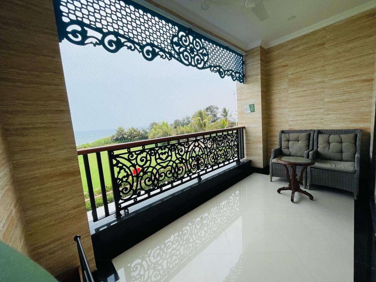 Un balcone con ringhiera decorativa, un divano in vimini e un tavolino.