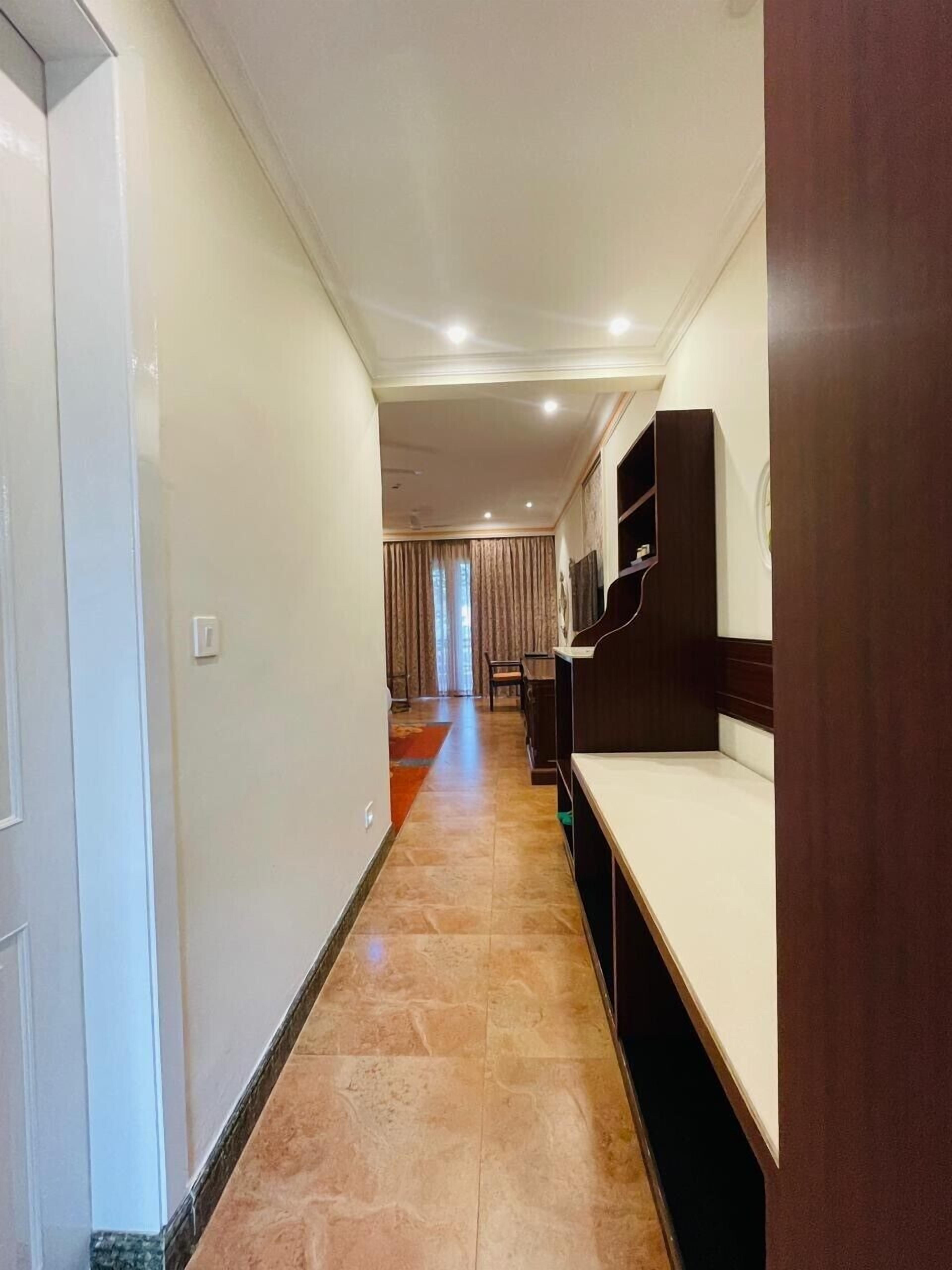 A hallway with a wooden bench, a TV mounted on the wall, and a door on the left.