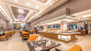 A modern hotel dining area with a central bar, multiple tables, and chairs. - Mayfair Palm Beach Resort  (Brahmapur)