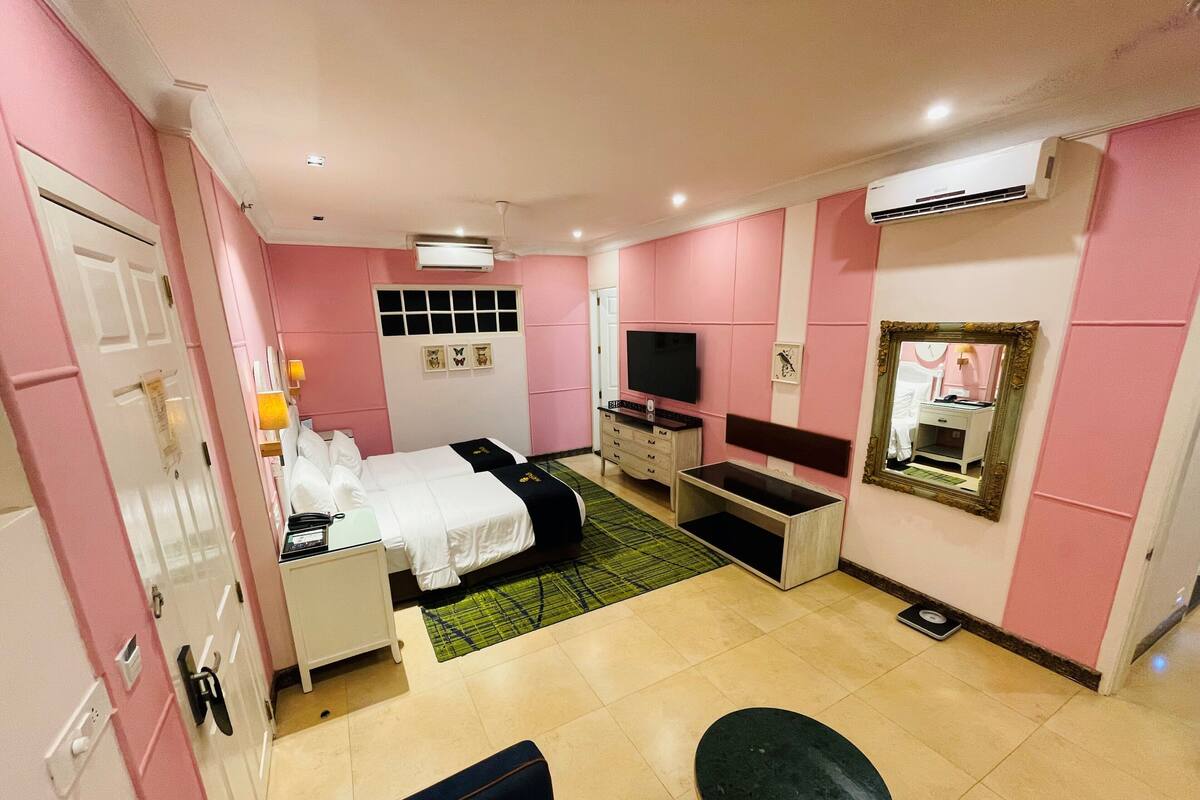 A hotel room with a bed, a TV, a desk, a chair, and a mirror.