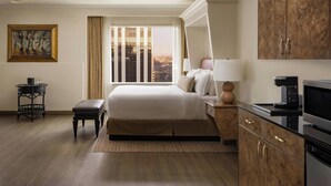 A hotel room with a bed, bedside table, lamp, coffee maker, and a view of the city. - The Davenport Tower, Autograph Collection (Spokane)