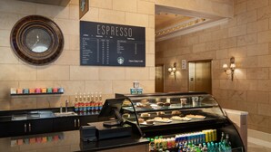 A coffee shop counter with a menu board, espresso options, and a variety of beverages and pastries. - The Davenport Tower, Autograph Collection (Spokane)