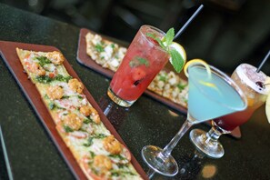 Eine Bar mit einer langen, rechteckigen Speisenplatte und zwei Cocktails.