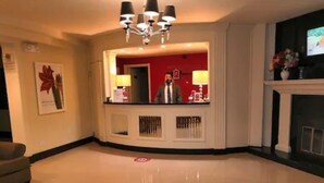A hotel lobby with a reception desk, a chandelier, a fireplace, and a large mirror.