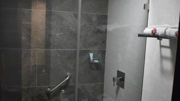 A modern bathroom with a glass shower enclosure, a towel rack with a towel, and a toilet.
