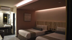 A hotel room with two beds, a bathroom, and a nightstand with a phone.