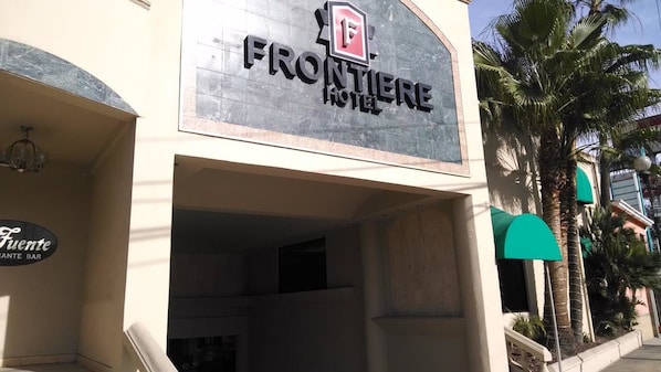 The exterior of the Frontier Hotel with a sign above the entrance.