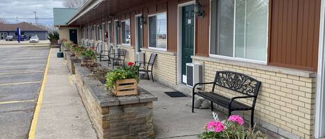 A motel with a row of rooms, outdoor seating, and a parking lot.