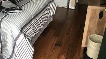 Quarto compacto com cama, uma pequena cozinha e banheiro.