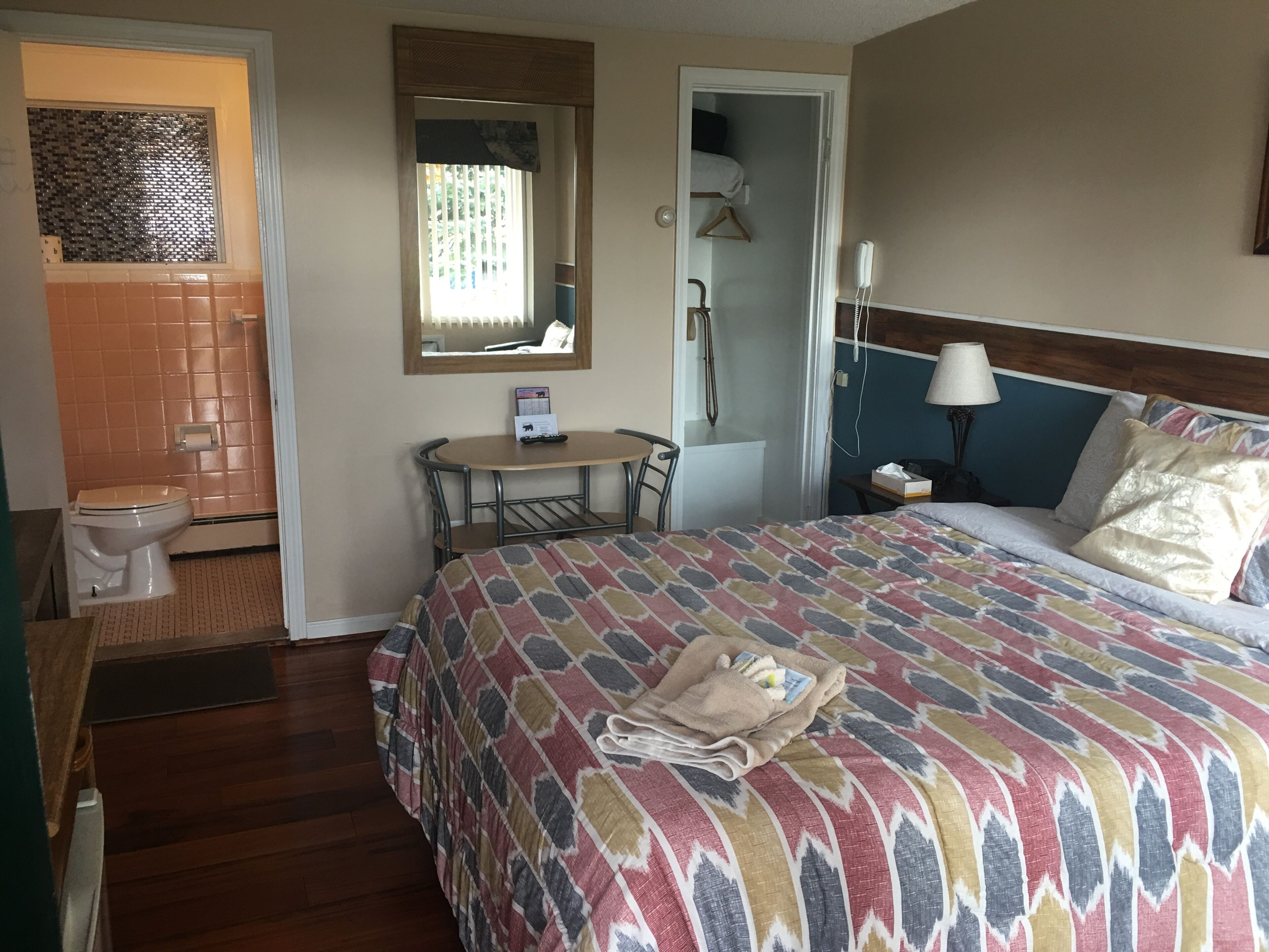 Une chambre d’hôtel comprenant un lit, une petite table, une chaise, des toilettes et un espace douche.