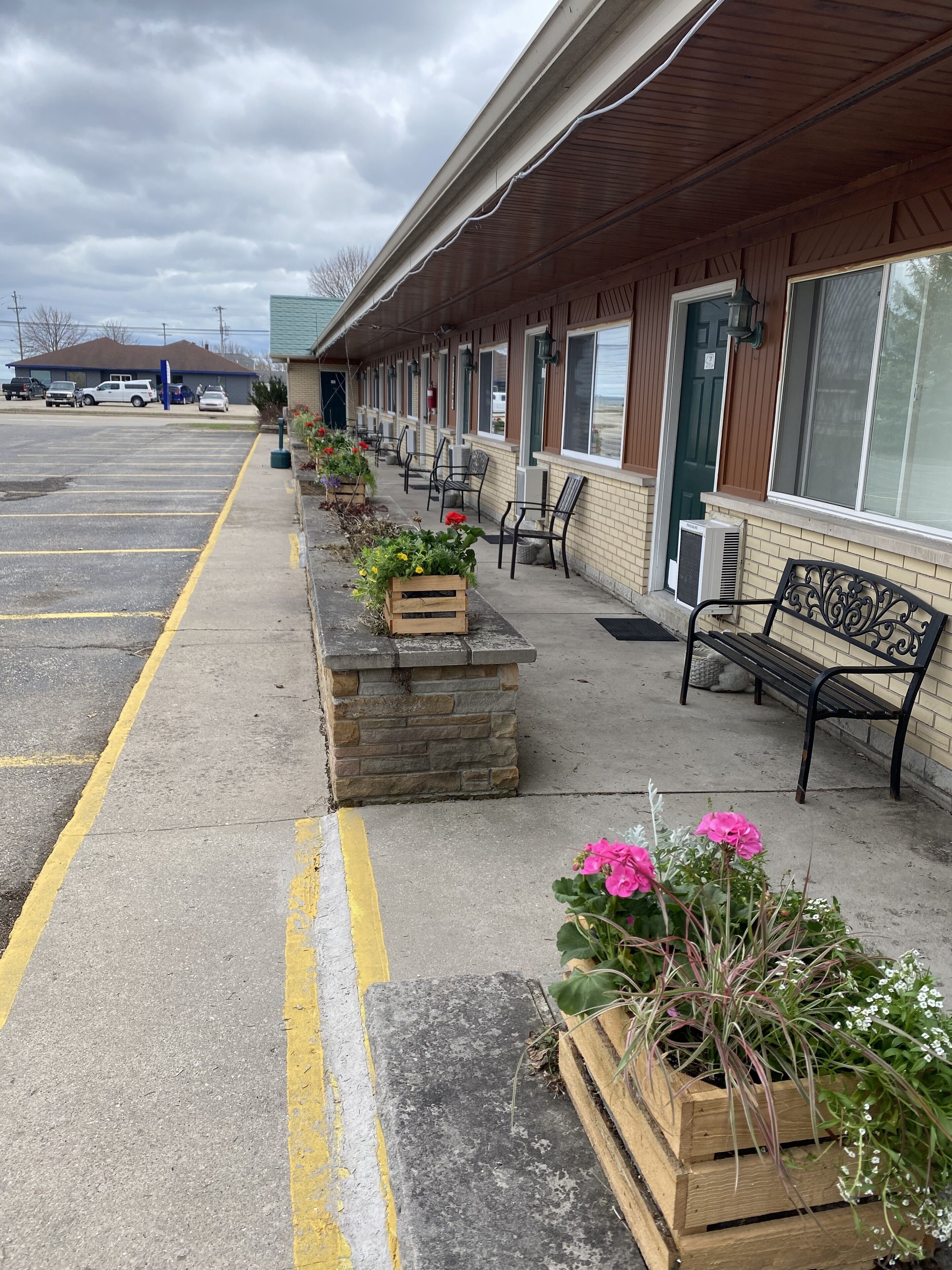 A motel with a row of rooms, outdoor seating, and a parking lot.