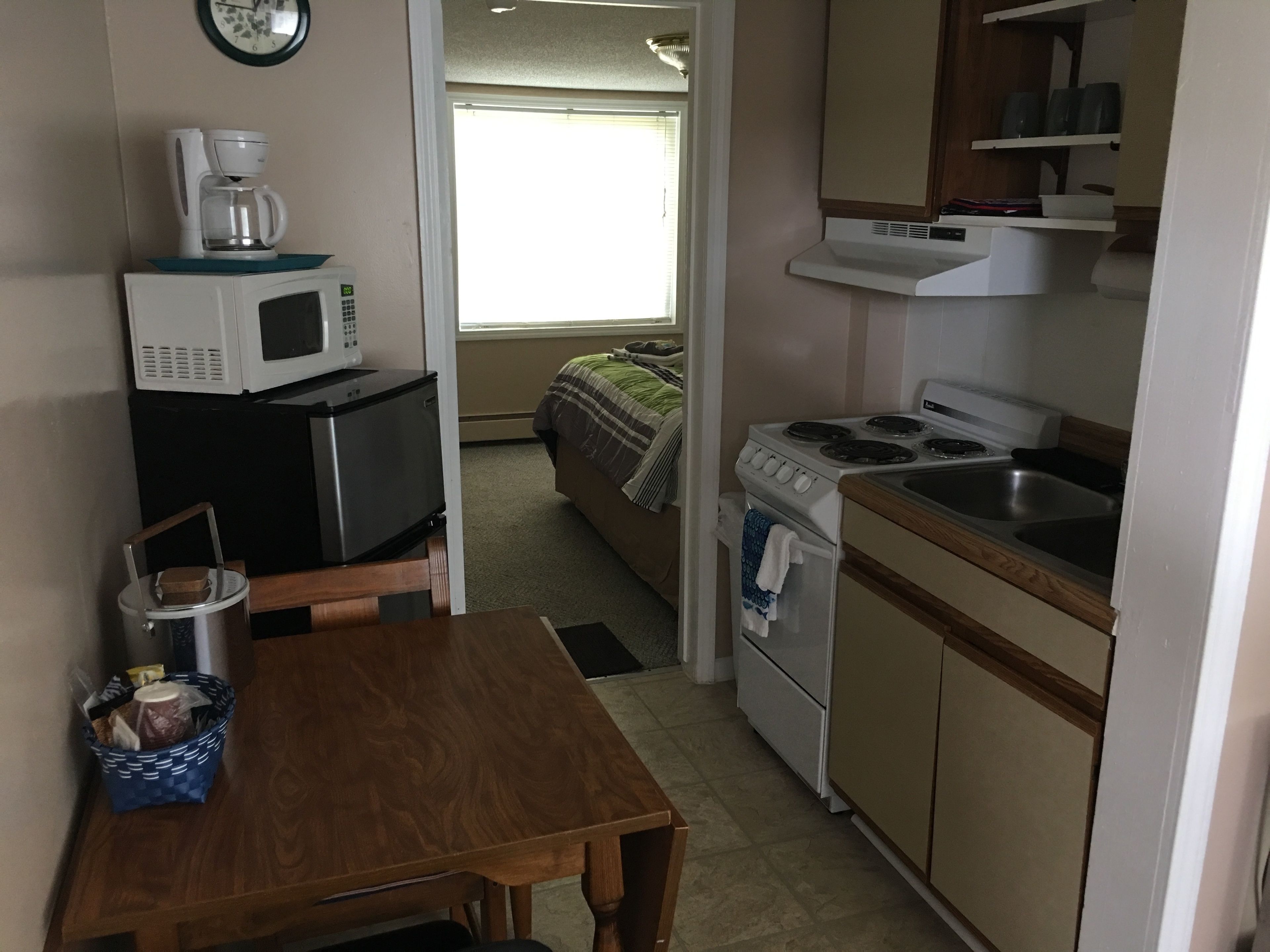 A compact kitchen with a microwave, coffee maker, stove, and sink.
