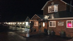 A rustic lodge with a welcoming sign, a covered porch, and a well-lit entrance. - Big Bear Lodge (Alpena)