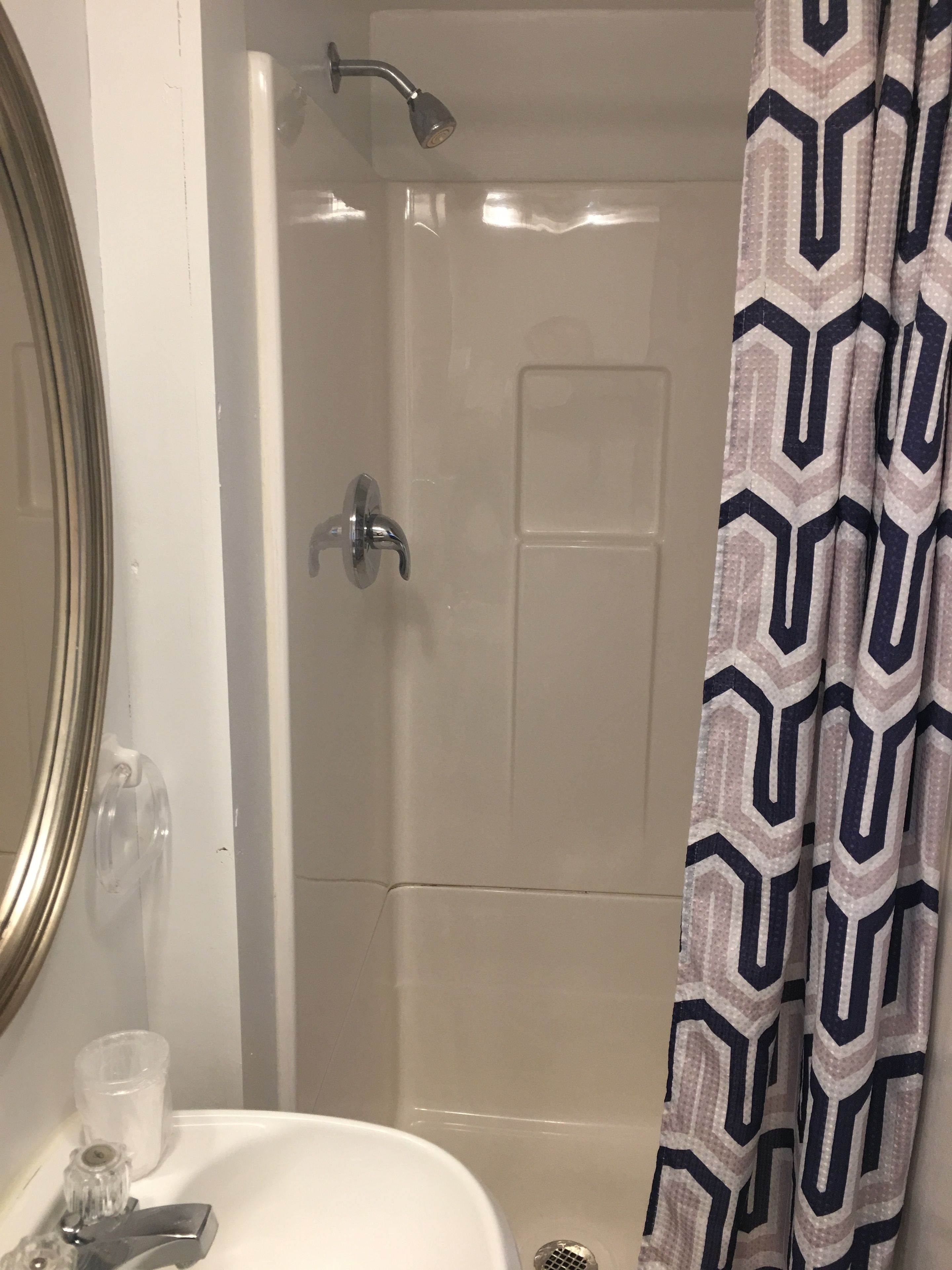 A bathroom with a shower, a sink, and a mirror.